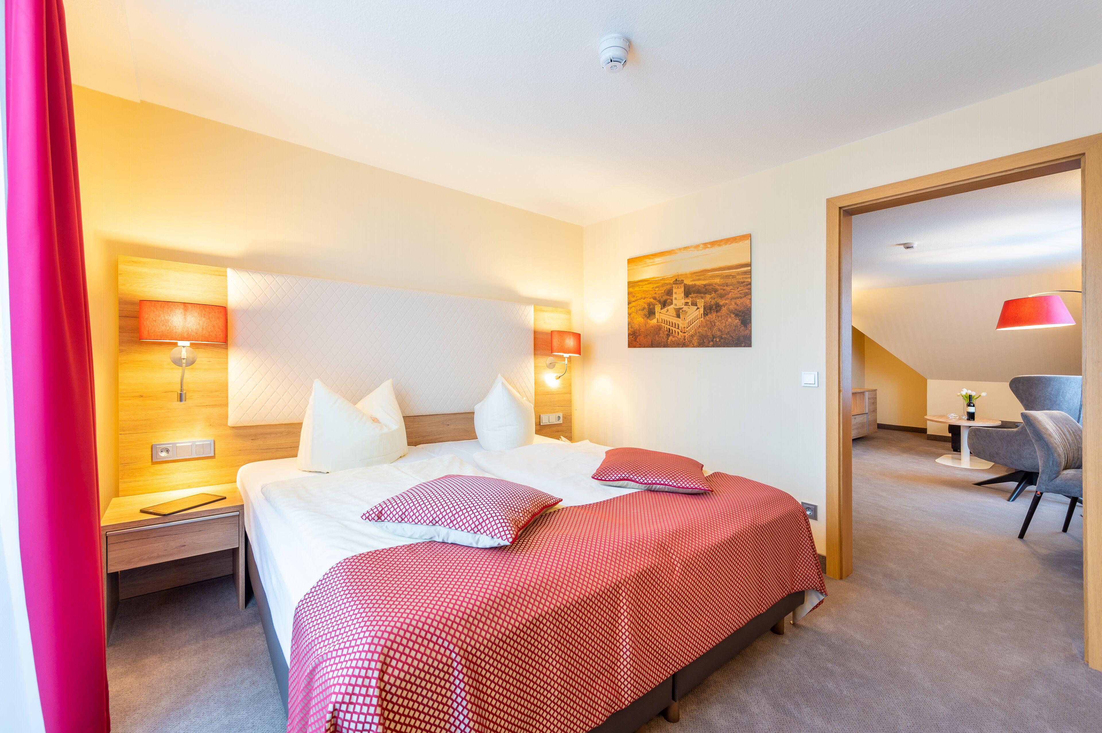Une chambre d’hôtel avec un lit, des lampes de chevet, une petite table avec un vase et une chaise.
