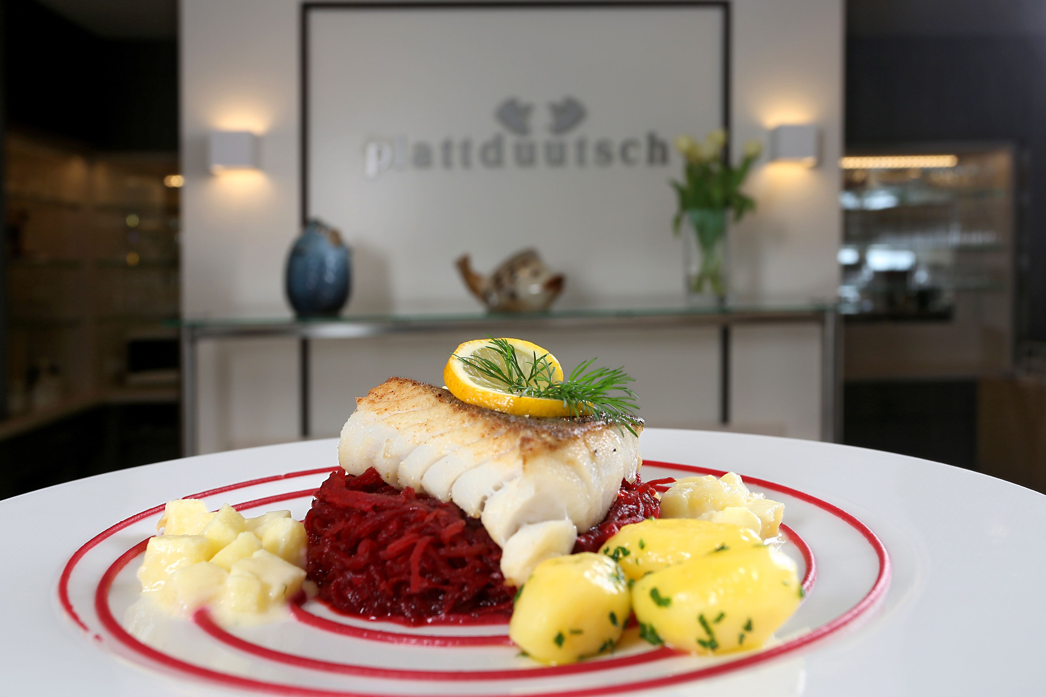 A plate of food with a fish fillet, red beetroot, and yellow potatoes.