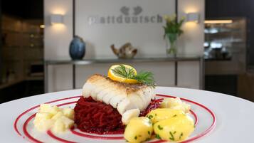 A plate of food with a fish fillet, red beetroot, and yellow potatoes.