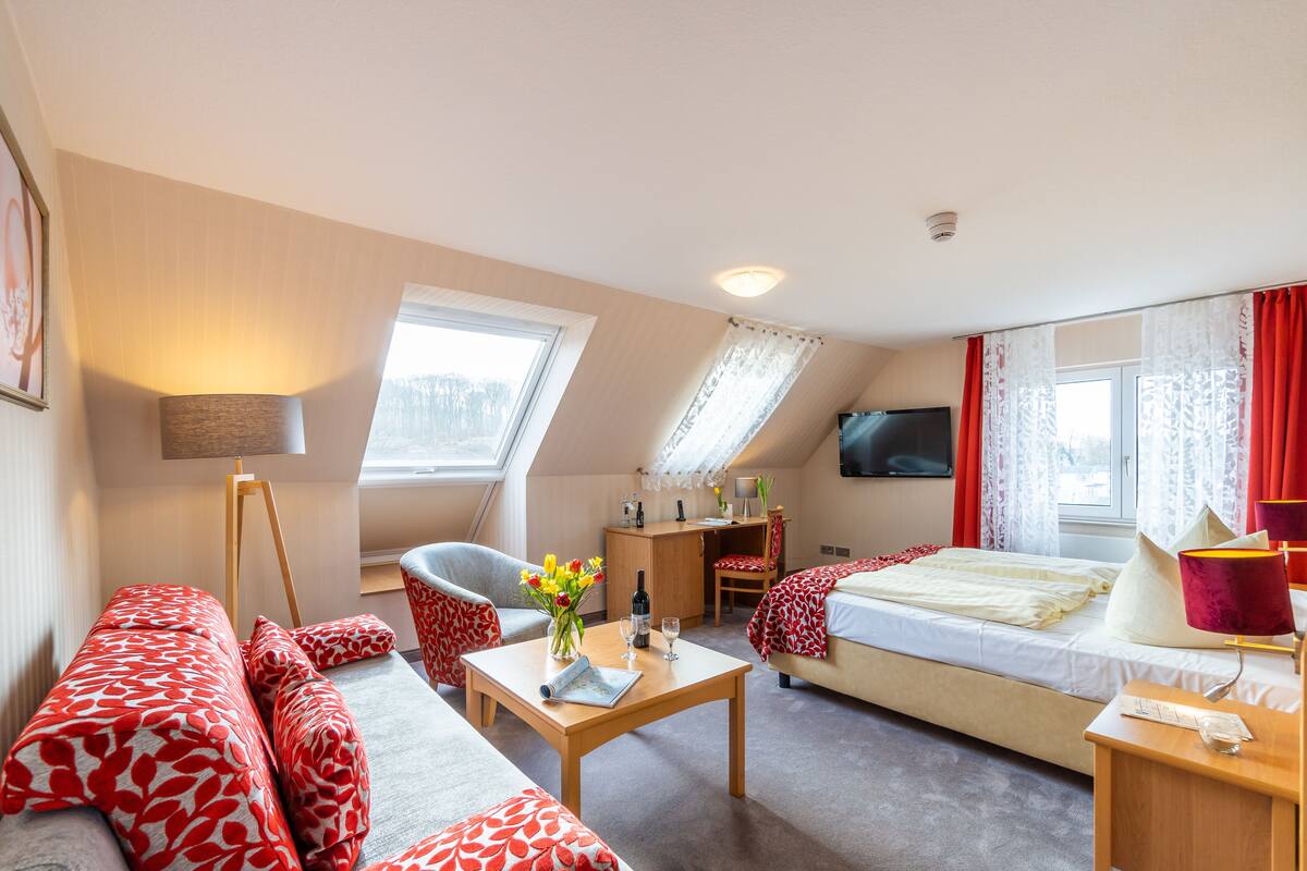Une chambre d’hôtel confortable, avec un canapé, un petit bureau, une chaise, un lit et un téléviseur.