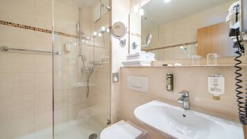 A modern bathroom with a glass shower enclosure, a white sink, and a large mirror.