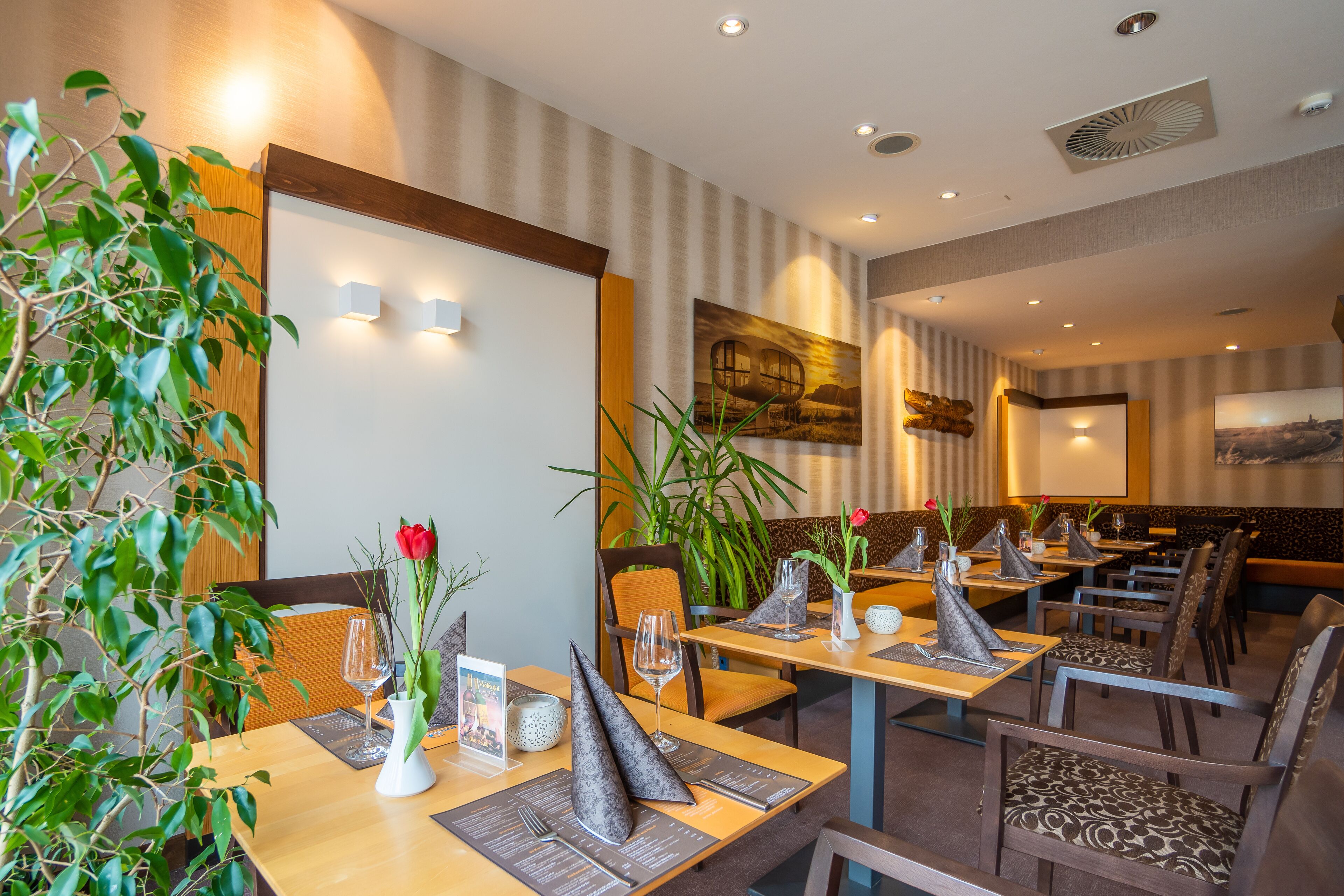 Een restaurant met houten tafels, stoelen en plantenpotten.
