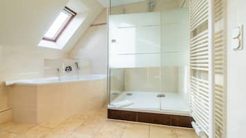 Un baño moderno con ducha envuelta en vidrio, bañera y tragaluz.