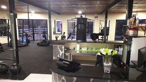 A gym with exercise equipment, a reception desk, and a view of the gym area. - Lusitaurus (Redondo)