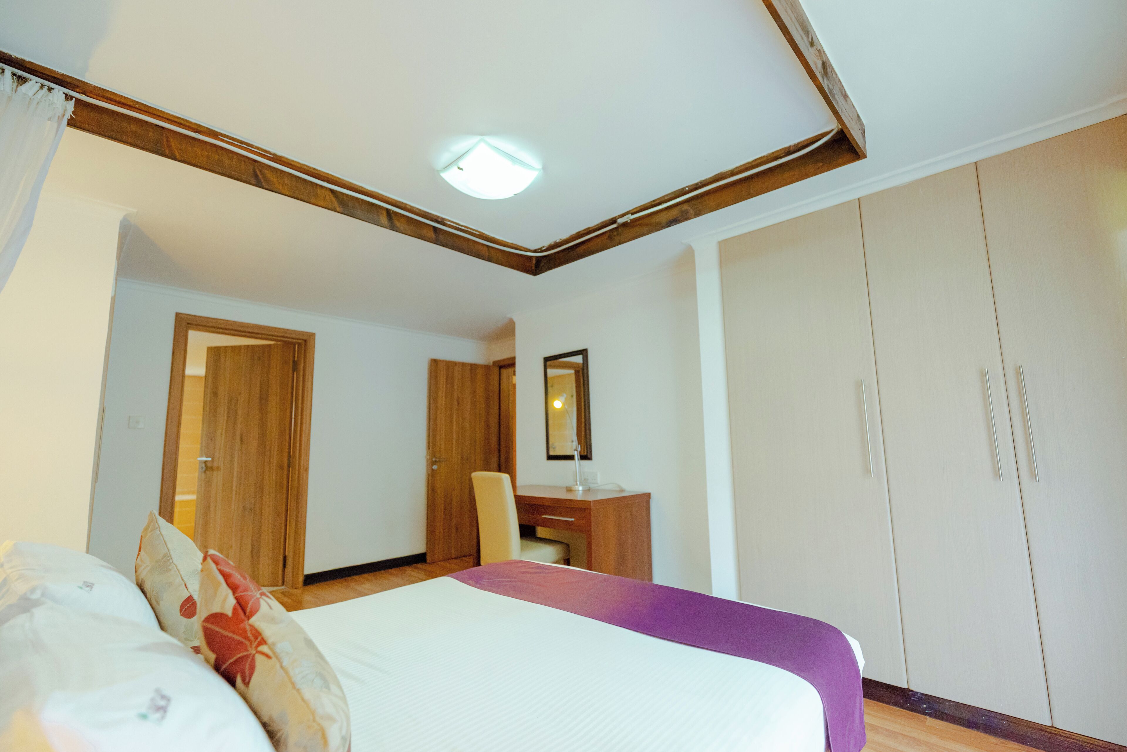 A hotel room with a bed, a desk, a chair, and a wardrobe.