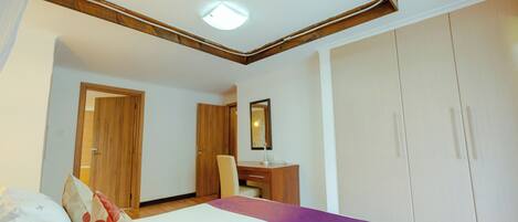 A hotel room with a bed, a desk, a chair, and a wardrobe.