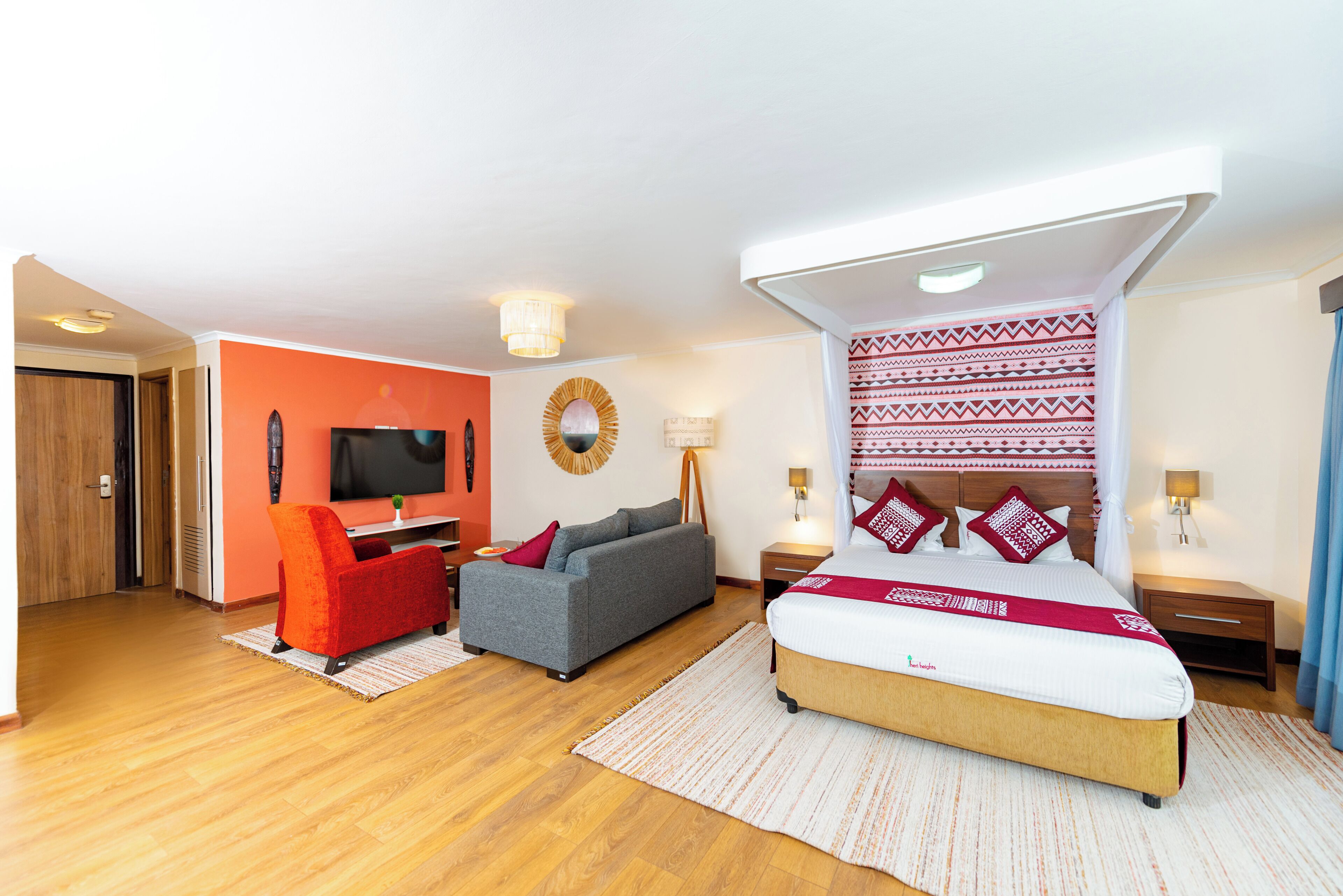 Una habitación de hotel moderna con cama, sofá, televisor y escritorio.