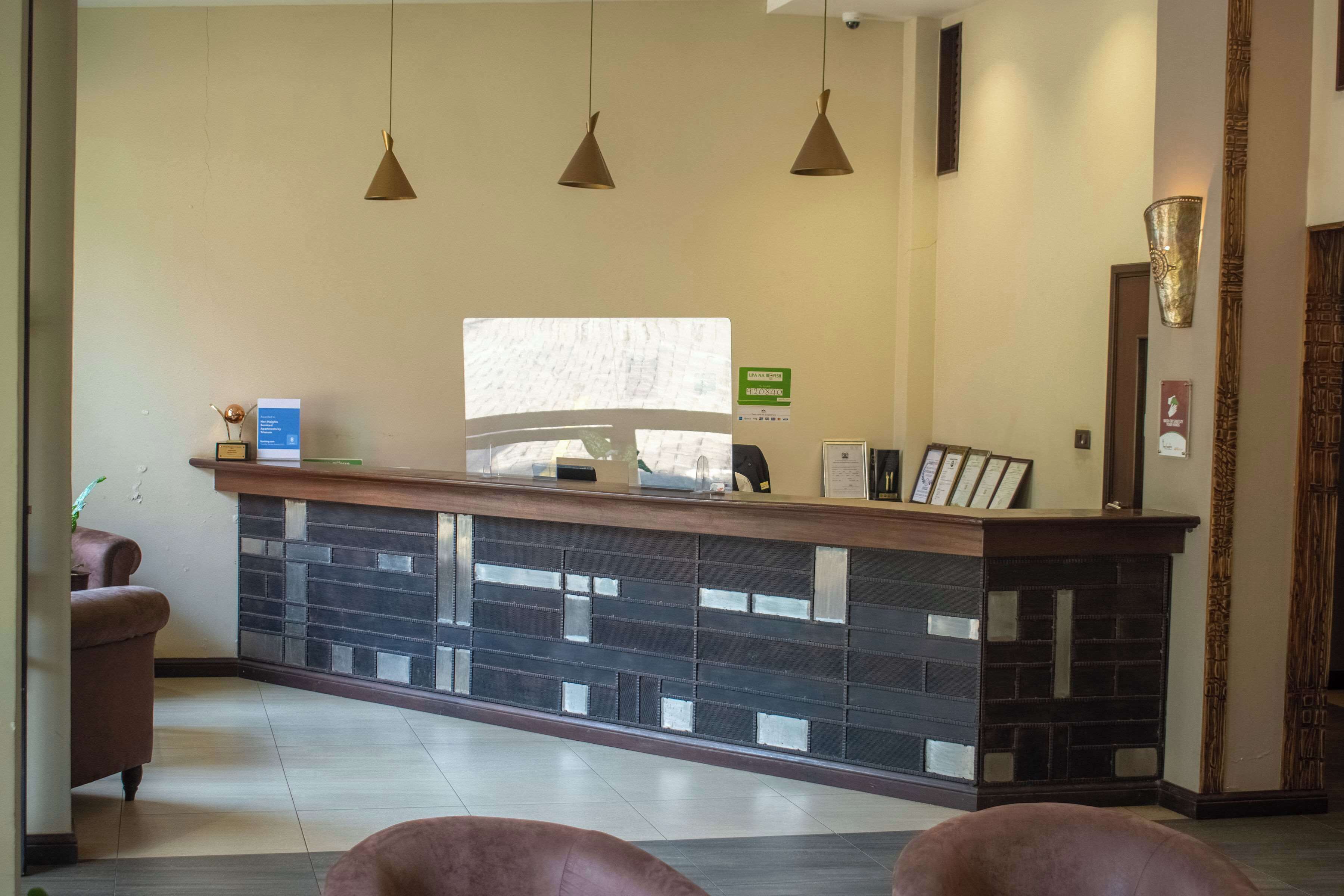 A reception area with a counter, three pendant lights, a reception desk, a framed picture, and a potted plant.