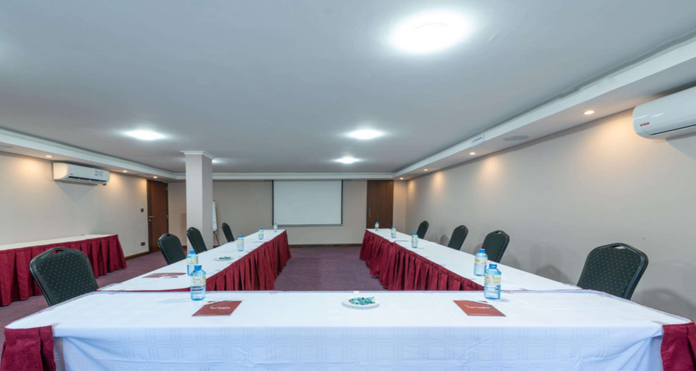 A conference room with a long table, chairs, and a projector screen.