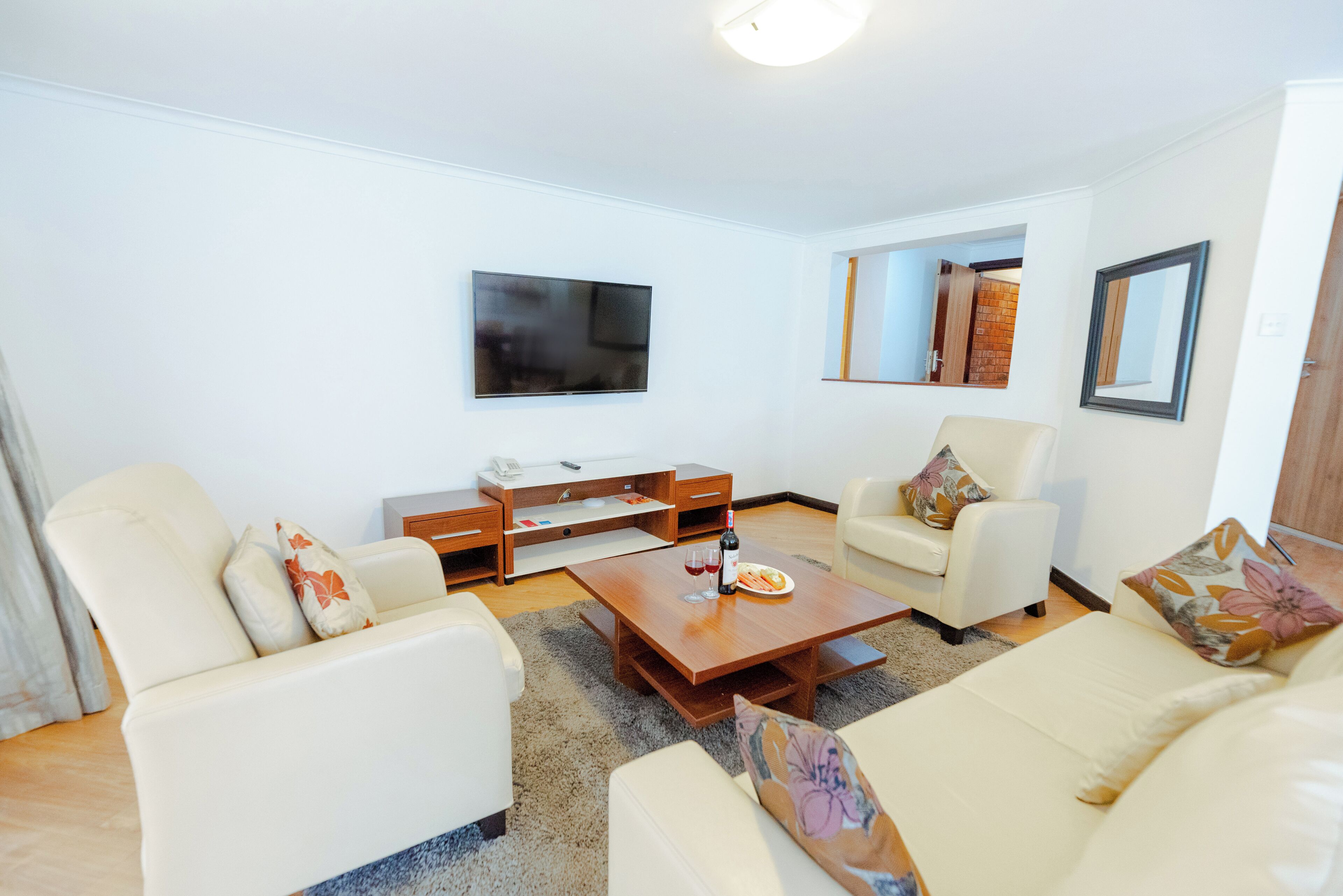 A living room with a flat-screen TV, a wooden coffee table, two sofas, and a small side table.