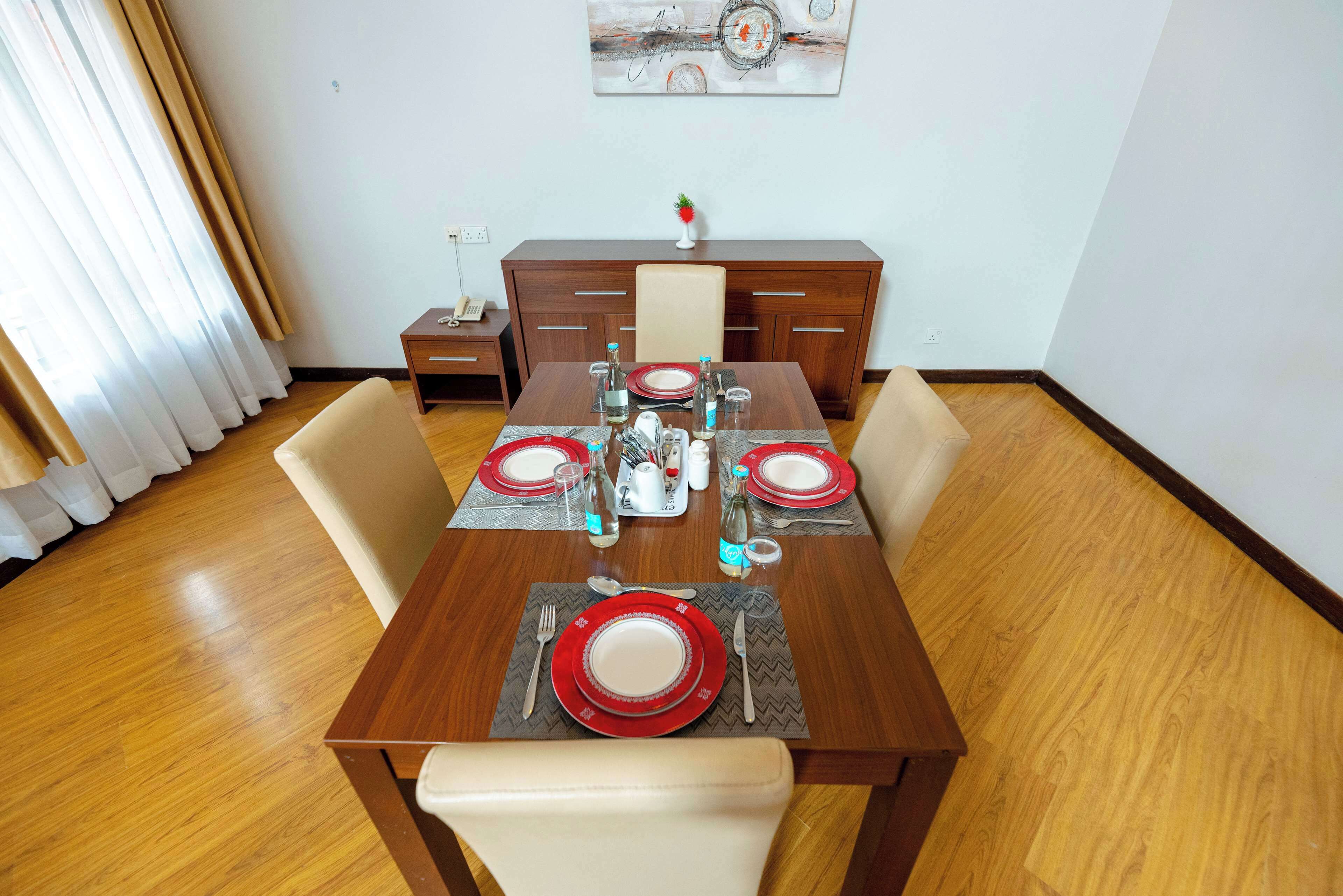 A dining area with a wooden table set for four, including plates, cutlery, and glasses.