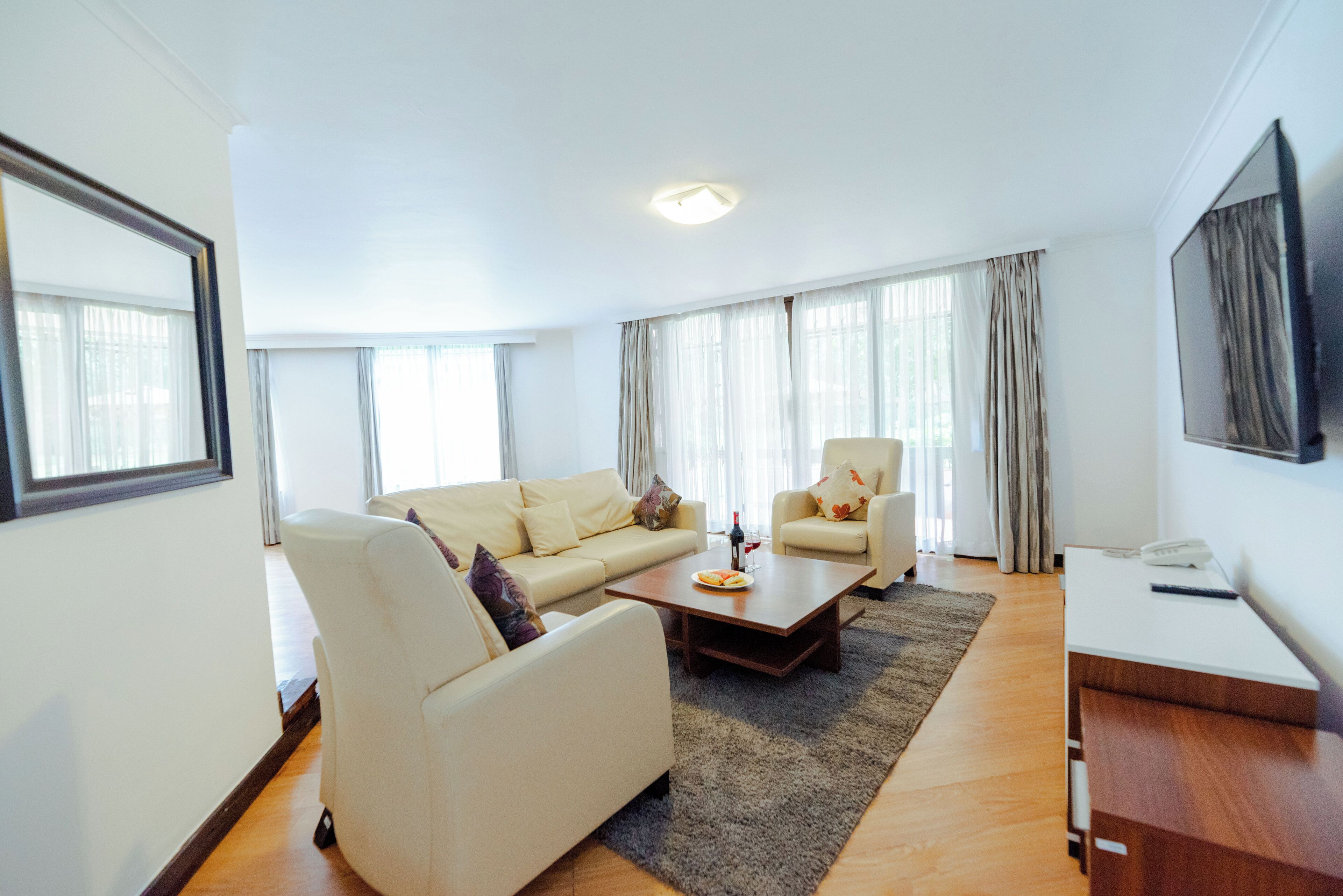 A modern living room with a sofa, armchair, coffee table, and a flat-screen TV.