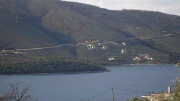 Un paisaje costero con una masa de agua, colinas y edificios dispersos.