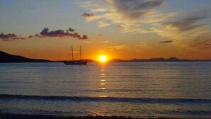 A sunset over a calm sea with a boat in the distance. - Almini Apartments (Igoumenitsa)