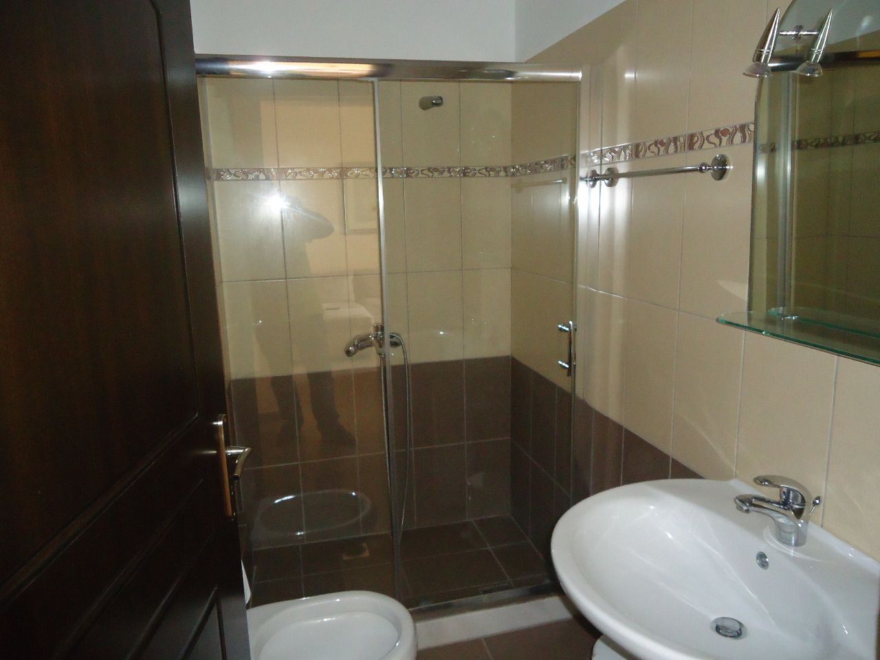 A bathroom with a glass shower enclosure, a white sink, and a toilet.