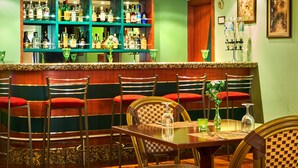 A bar area with multiple shelves of liquor bottles, a counter, and seating with red cushions. - Feronya Hotel (Istanbul)