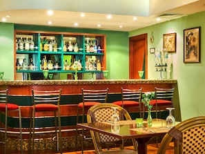 A bar area with multiple shelves of liquor bottles, a counter, and seating with red cushions.