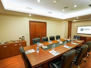 A conference room with a long table, chairs, water bottles, and a screen displaying the hotel name. - Feronya Hotel (Istanbul)