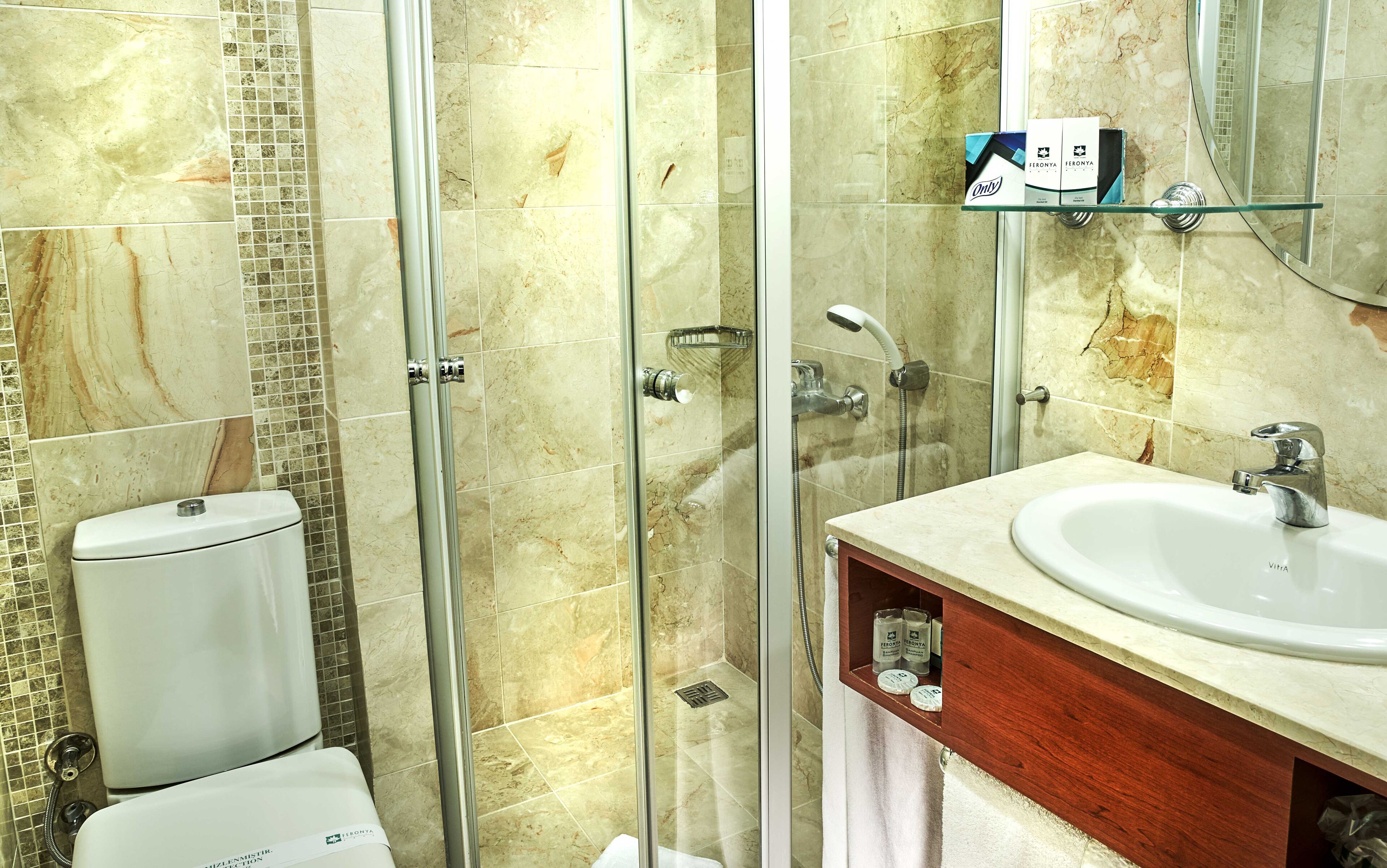 A bathroom with a glass shower enclosure, a toilet, and a sink with a mirror above it.