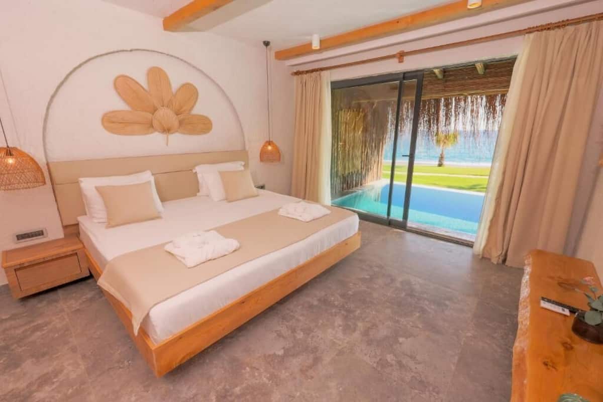 Un dormitorio amplio con una cama grande, vistas a una piscina y un cabecero de madera.
