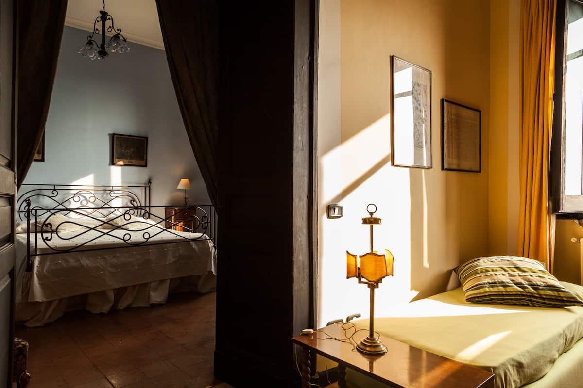 A bedroom with a bed, a nightstand, a lamp, and a window with curtains.