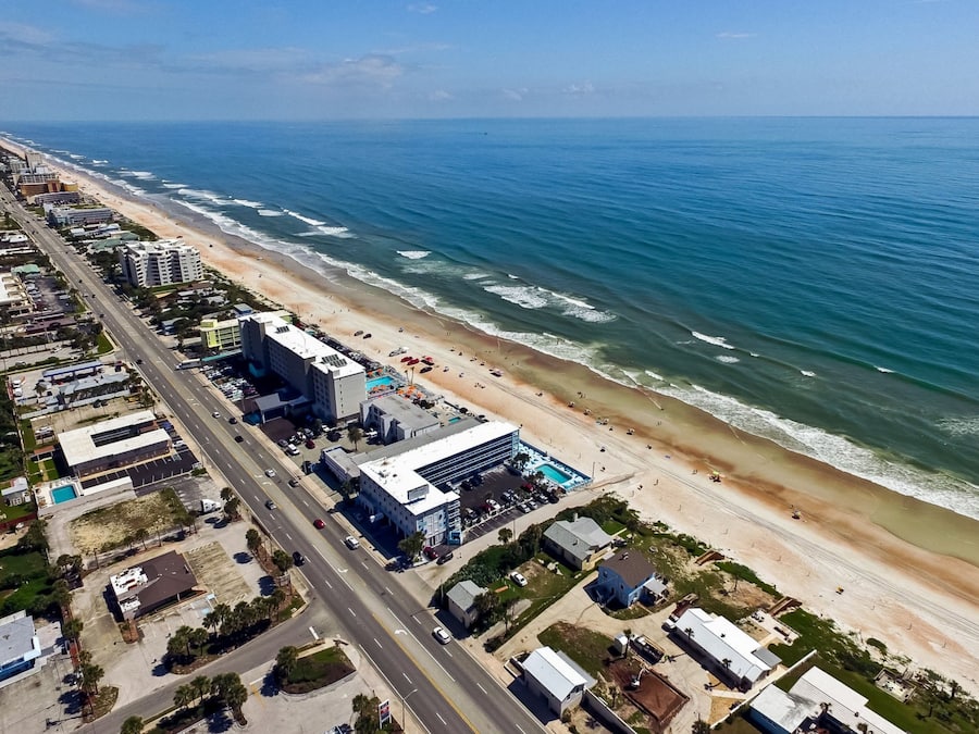 Vista aérea de una ciudad costera con playa, edificios y una carretera.
