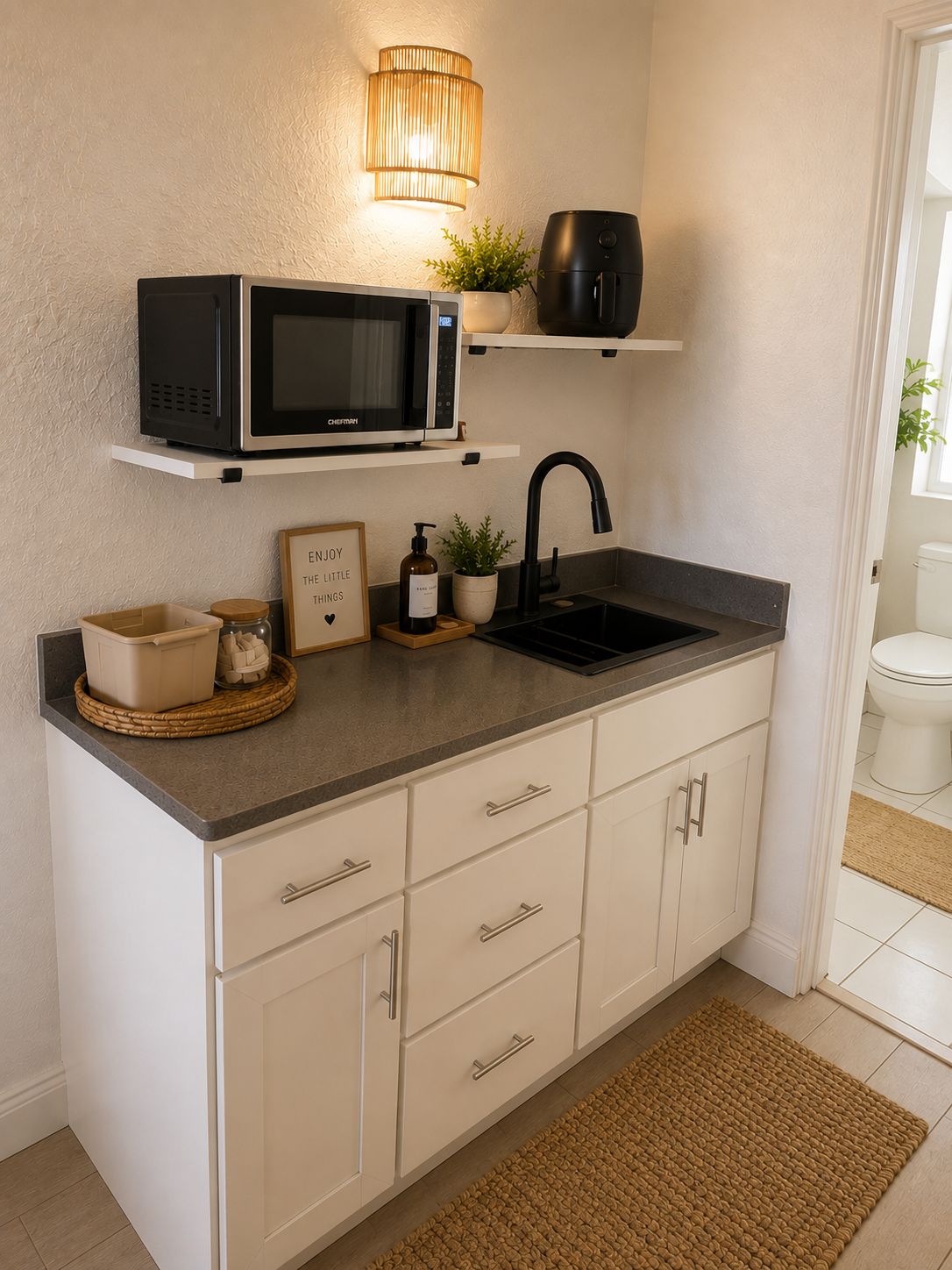 Una cocina con microondas, un lavabo y una pequeña planta en maceta.