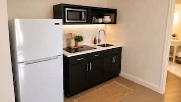 A modern kitchen with a refrigerator, microwave, sink, and black cabinets.