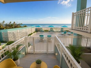 Een balkon met uitzicht op de oceaan, buitenmeubels en bloempotten.
