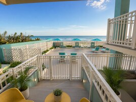 A balcony with a view of the ocean, outdoor seating, and potted plants.