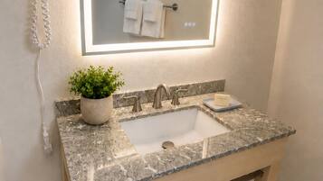 A bathroom with a marble sink, a potted plant, a towel rack, and a wall-mounted phone.
