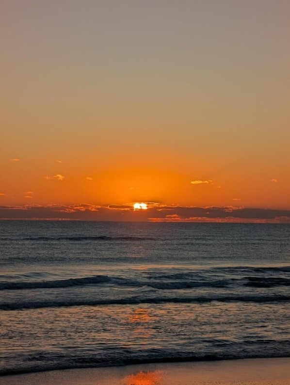 Un atardecer sobre el océano con olas acercándose a la orilla.