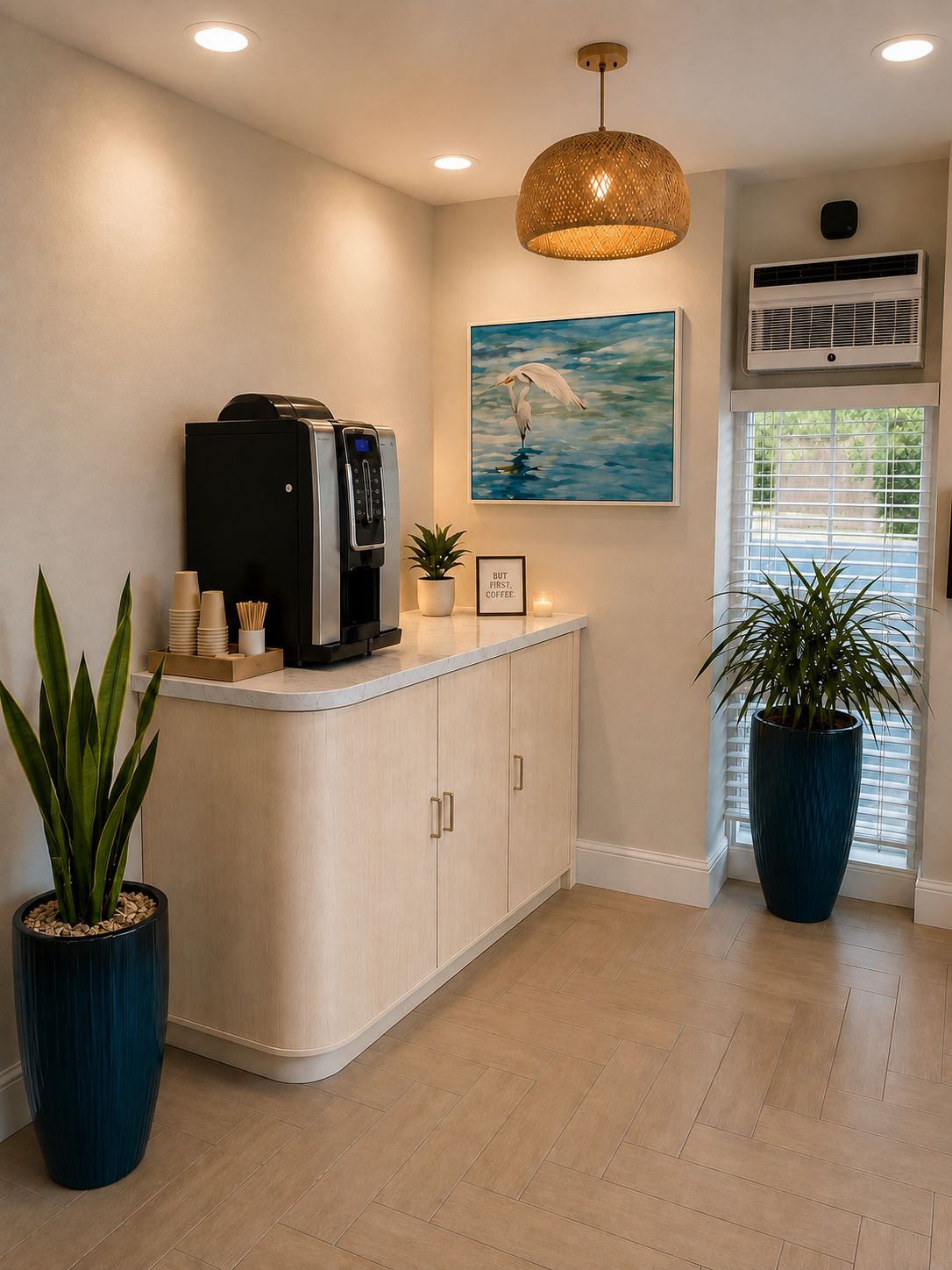 A reception area with a coffee machine, a painting of a bird, and potted plants.