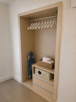 A walk-in closet with a wooden door, a hanging rod, a blue towel, and a basket with towels.
