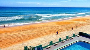 Een strand met een zwembadgedeelte, inclusief een zwembad, ligbedden en een hek.