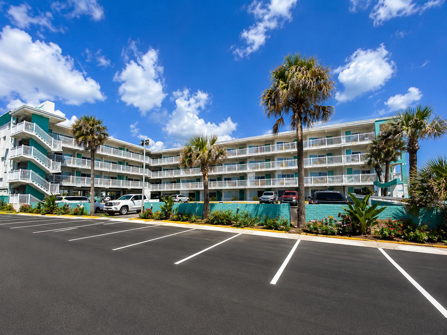 A multi-story hotel with a parking lot and palm trees.