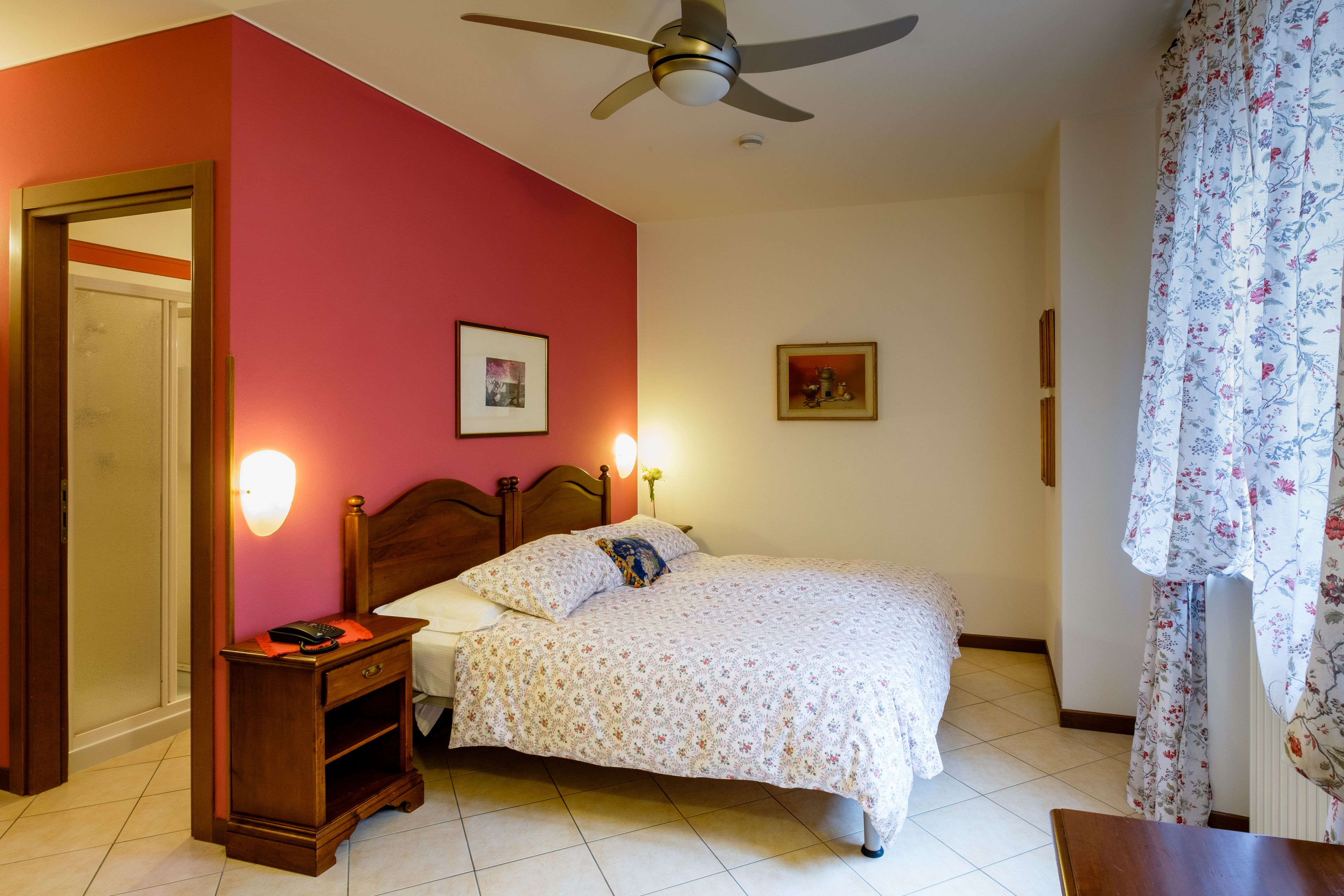 Una camera da letto con un letto, un comodino, una ventola a soffitto e luci a parete.