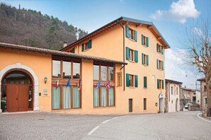 A two-story building with a large arched entrance, multiple windows with green shutters, and a sign indicating it is a hotel. - Hotel Tre Punte (Gargnano)