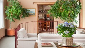 A cozy living room with a white sofa, a coffee table, and two potted plants. - Hotel Tre Punte (Gargnano)