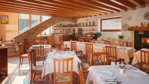 A restaurant with wooden beams, stone staircase, and a fireplace. Tables are set with white tablecloths and chairs. - Hotel Tre Punte (Gargnano)