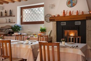 A dining area with tables set for meals, a fireplace, and decorative items on shelves. - Hotel Tre Punte (Gargnano)