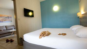 A hotel room with a bed, a television mounted on the wall, a sofa, and a small table.