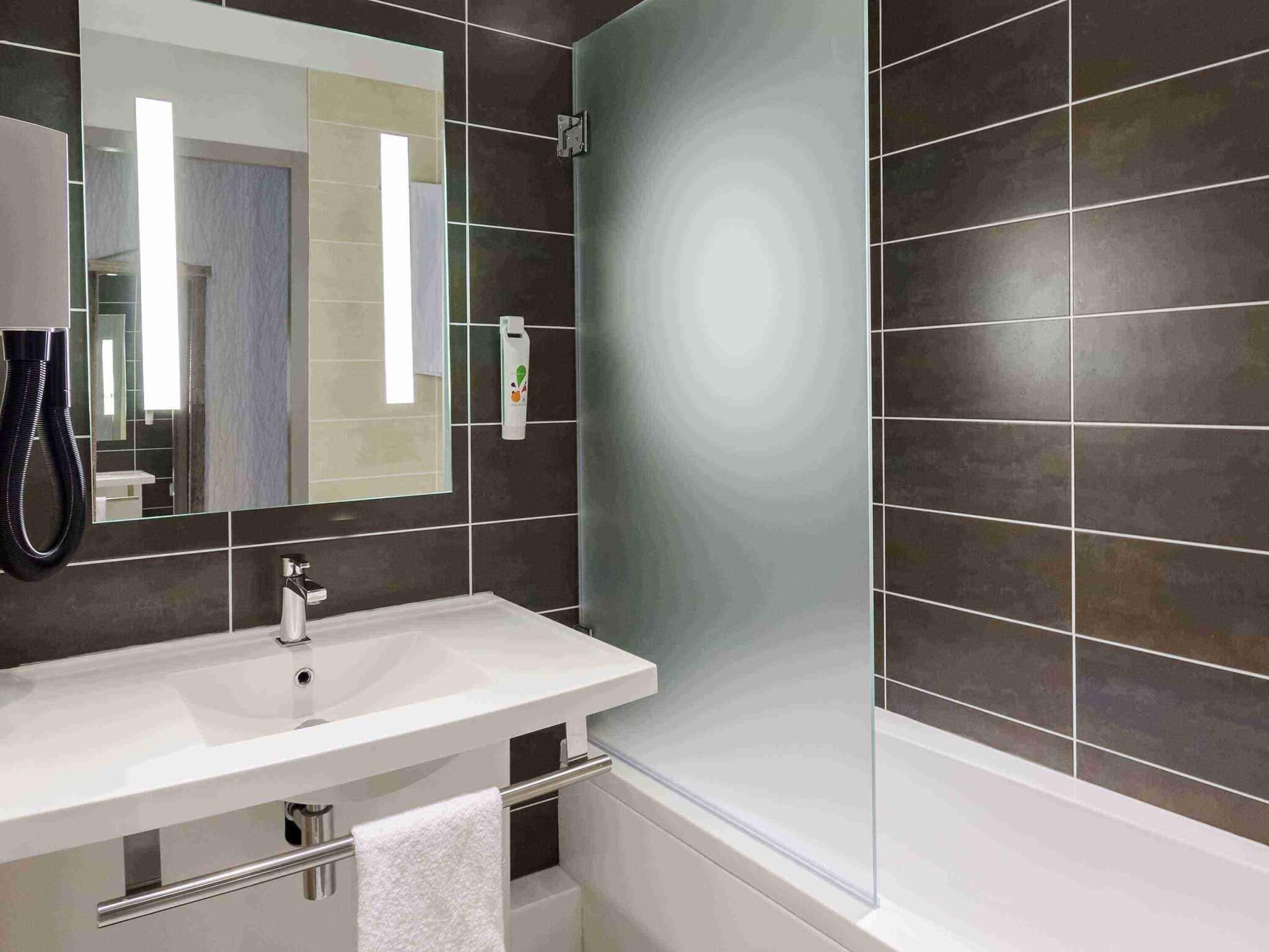 A modern bathroom with a white sink, a mirror, and a glass shower enclosure.