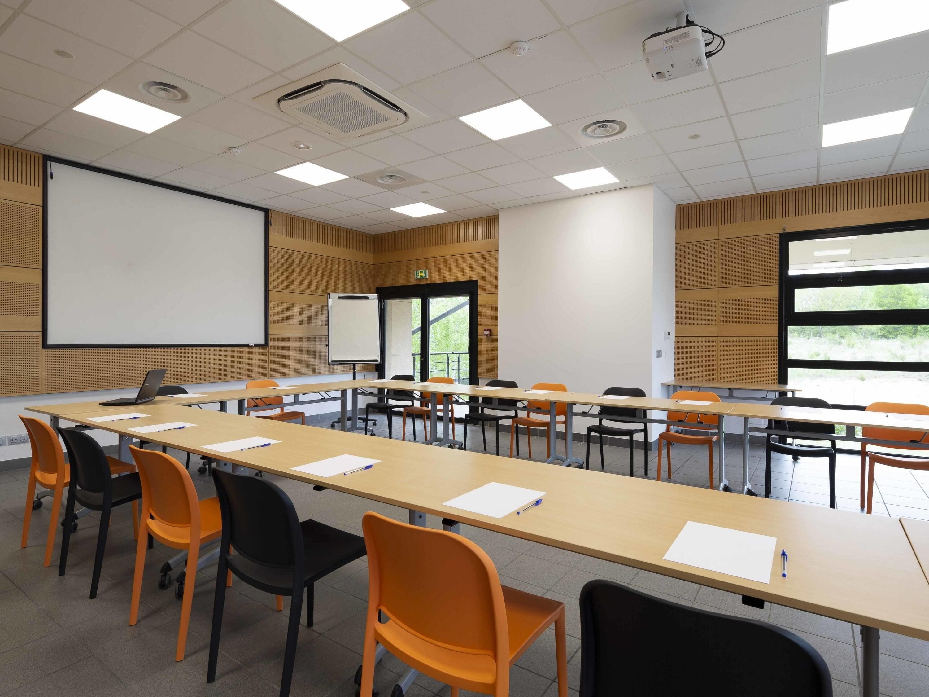 A conference room with a long table, chairs, a projector screen, and a whiteboard.