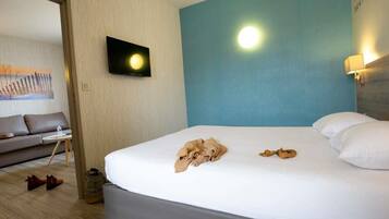 Ein Hotelzimmer mit einem Bett, einem Fernseher, einer Wandleuchte und einem Bild an der Wand.