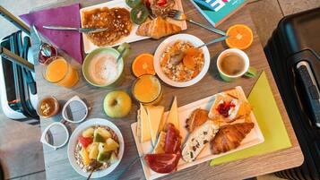 A breakfast buffet with various food items and a book on the table.