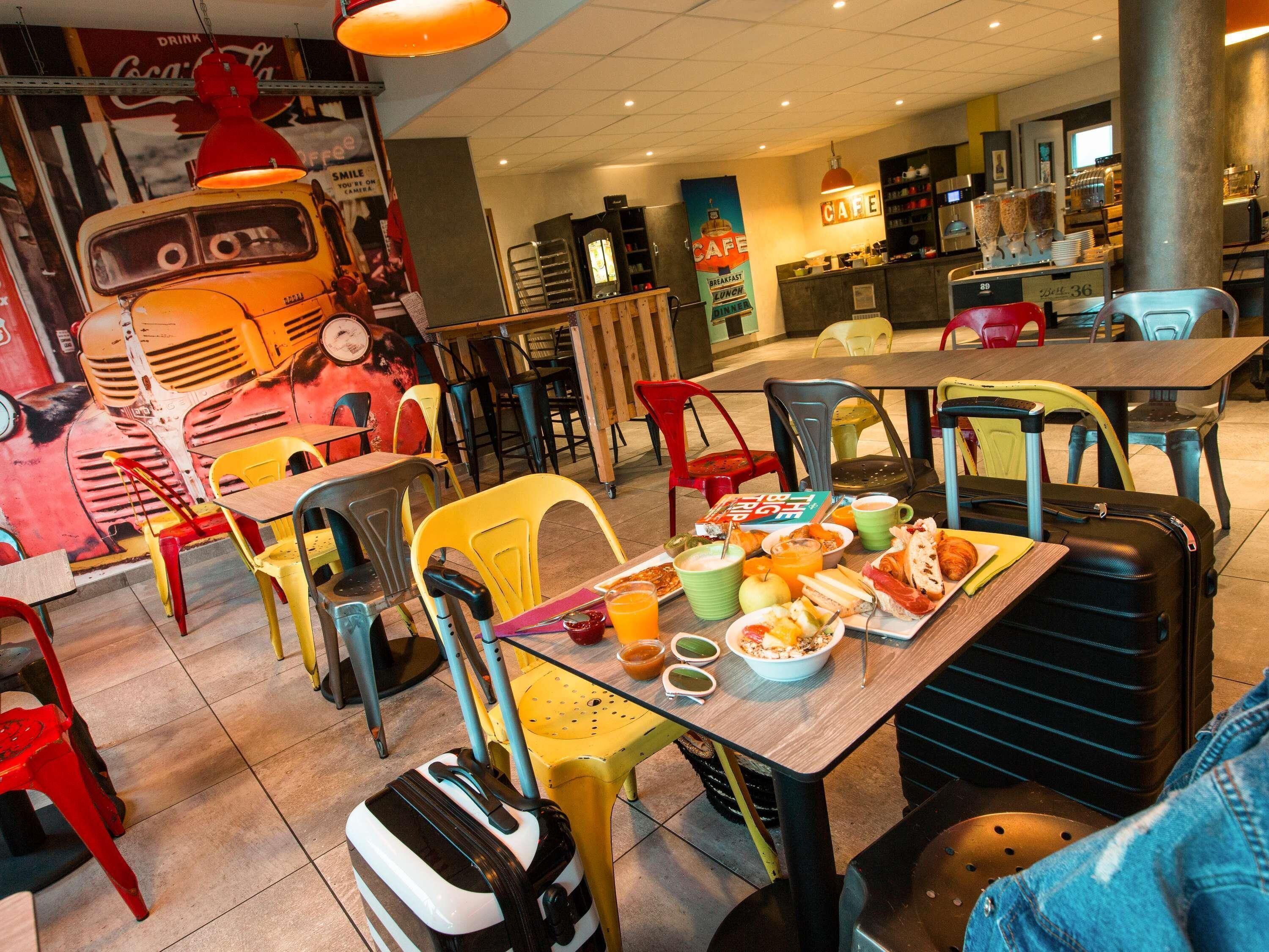 A dining area with colorful chairs, a table with food, and a suitcase.