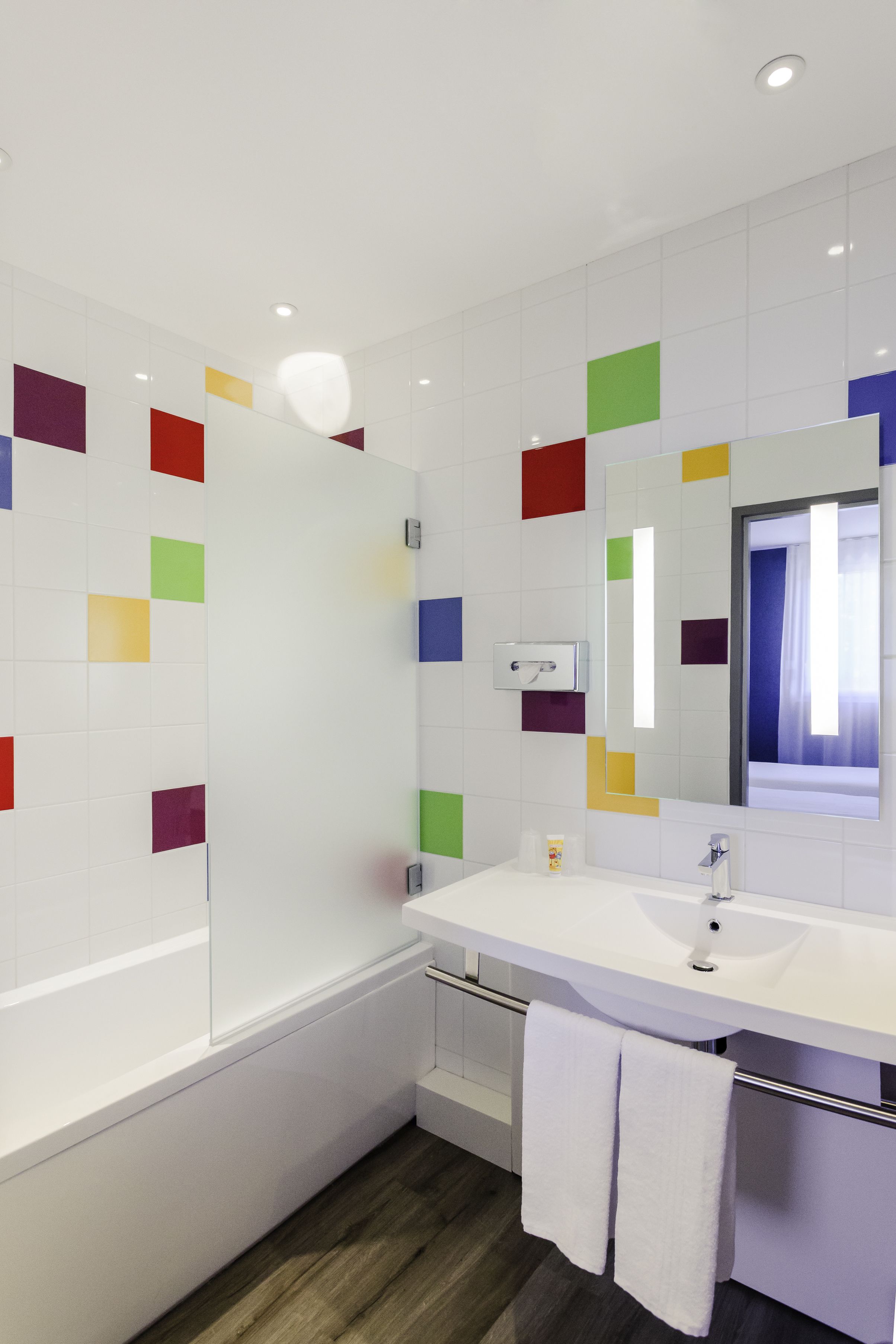 Un baño moderno con una bañera blanca, un lavabo blanco y un espejo sobre el lavabo.