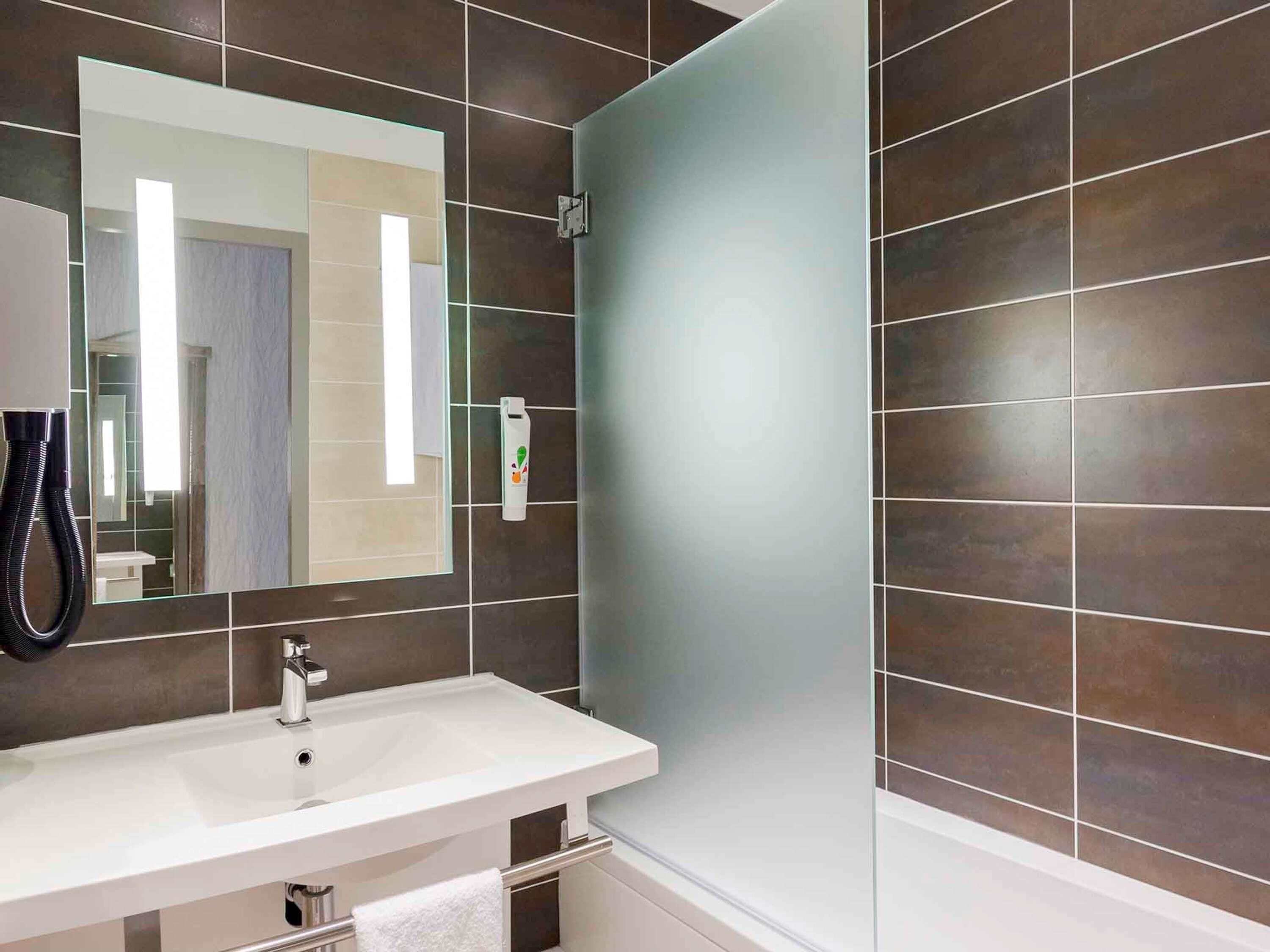 A modern bathroom with a white sink, a mirror, and a shower.