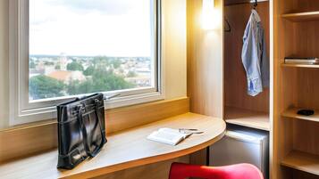 Una habitación con un escritorio, una silla roja, un bolso negro, una libreta y un bolígrafo.